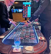 Roulette table with woman dealer at casino party